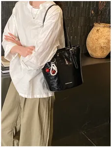 Detail of glossy black shoulder bag with cherry pearl charm and Fashion & Bags text