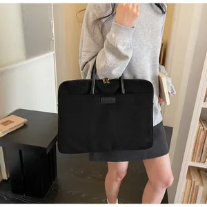 Detail van zwarte suède laptoptas met leren handvatten en minimalistisch logo-accent