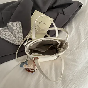 Chic sac à main crème avec intérieur multicouche et pendentif peluche décoratif