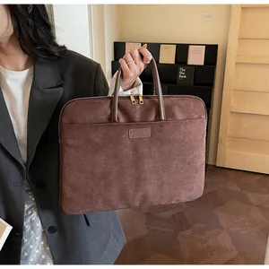 Close-up van bruine suède laptoptas met leren logo gedragen door kantoormedewerker