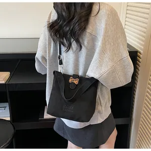 Detail view of black faux suede bucket bag with leopard print bow and shoulder strap