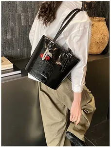 Detail of black patent leather bucket bag with cherry pendant and FASHION lettering