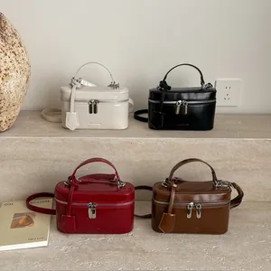 Sacs à main brillants en crème, noir, rouge et caramel posés sur des marches en pierre
