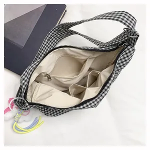 Detail of checkered tote bag interior with zipper pocket and colorful tassel accessory