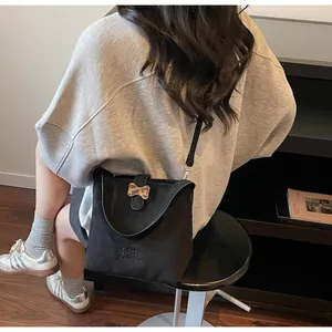 Detail of black suede bucket bag featuring embroidered logo and leopard bow accent