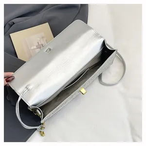 Détail intérieur d'un sac de soirée argenté métallisé avec fermoir rotatif doré