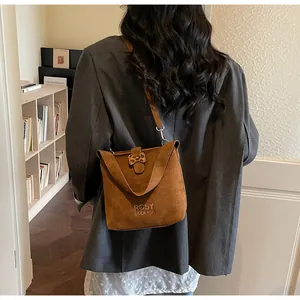 Detail of a brown suede bucket bag featuring leopard print accents and embroidery