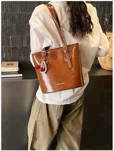 Brown oil-wax leather tote with cherry pearl charm shown on model in a minimalist setting