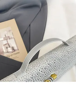 Détail du sac à bandoulière en strass argenté avec poignée en cuir gris et fermoir doré