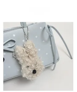 Close-up of blue polka dot bag with a white plush cartoon charm and ribbon detail
