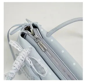Detail of light blue polka dot handbag showing silver metal zipper and lace woven trim