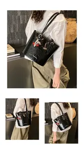 Detail of black glossy wrinkled tote bag with cherry pearl charm and adjustable strap