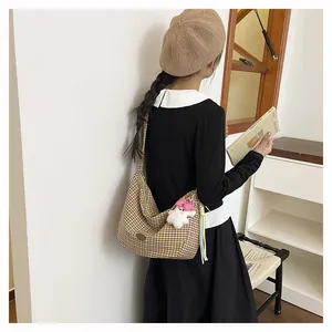 Detail view of large checkered tote bag with plush charm on a casual model outfit