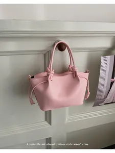 Detailed view of pink leather tote bag featuring refined texture and knot handle design