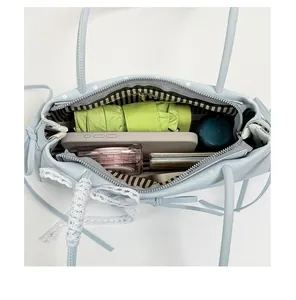 Top view of blue polka dot bag interior holding umbrella, phone, and cosmetics