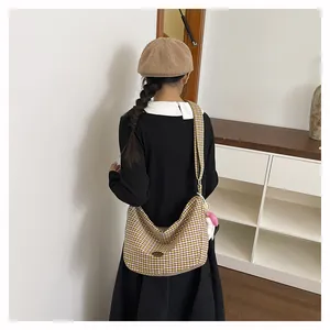 Detail of large capacity checkered canvas tote bag with pink plush pendant on shoulder