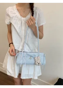 Detail of light blue polka dot shoulder bag with bow, lace ribbon and cute puppy charm