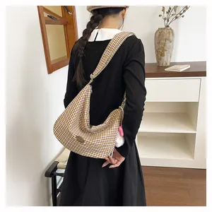 Detail of checkered shoulder bag with wide strap and white plush charm accessory