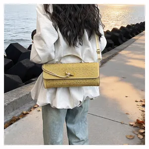 Détail d'un sac de soirée doré orné de strass avec un fermoir nœud métallique au coucher du soleil