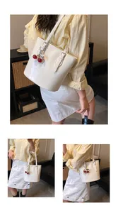 Close-up of cream faux leather bucket bag featuring a decorative pearl cherry charm