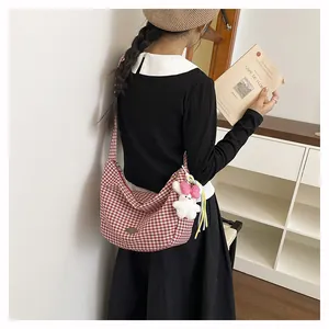 Close-up of red checkered canvas hobo bag featuring a cute bunny plush charm on a model