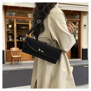 Détail du sac bandoulière en strass noirs avec fermoir doré et poignée élégante
