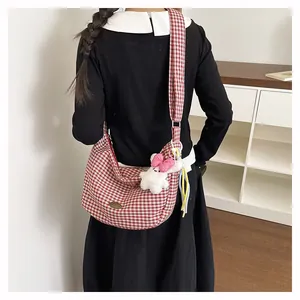 Detail of red checkered crossbody tote bag with a white plush bunny charm