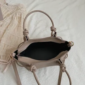 Minimalist khaki leather tote bag with braided knot handle and gold hardware detail