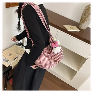 Detail of red and white checkered tote bag with a cute plush rabbit charm on strap