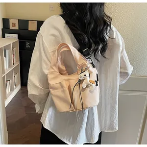 Détail du sac seau en toile rose clair avec bandoulière noire et breloque poney