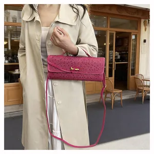 Gros plan d'un sac bandoulière rose en strass avec fermoir doré porté par un mannequin