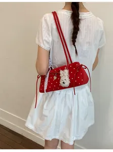 Detail of red polka dot baguette bag with side bow and cute white puppy plush charm