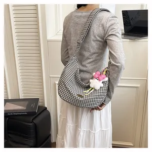 Close-up of a checkered tote bag with a cute plush bunny charm and adjustable strap