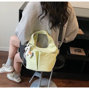 Détail du sac en toile vert clair avec poches avant et bandoulière noire amovible