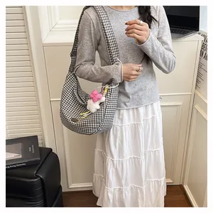Close-up of black and white checkered tote bag with a plush pink bow on a model