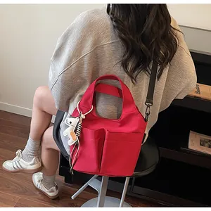 Détail du sac fourre-tout rouge avec poches avant et breloque cheval blanc en situation