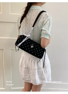 Polka dot baguette bag with lace strap and heart pendant detail on a model
