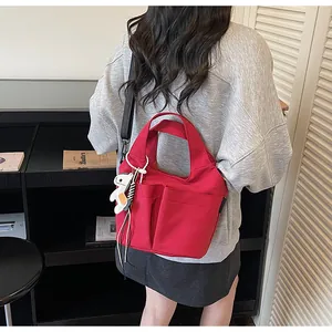 Détail du sac en toile rouge avec deux poches avant et un pendentif animal de dessin animé