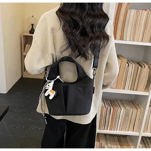 Détail du sac bandoulière en toile noire avec multi-poches et breloque poney mignonne