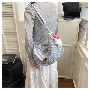 Blue and white checkered crescent tote bag with cute plush rabbit charm on broad strap