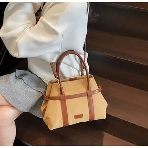 Dettaglio della borsa tote a contrasto con finiture in pelle e fibbie dorate