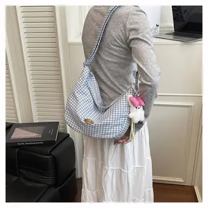 Blue gingham hobo bag detail with white bunny plush charm and metallic logo plate