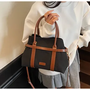 Dettaglio borsa tote in tela nera con cinturini in pelle marrone e tracolla regolabile