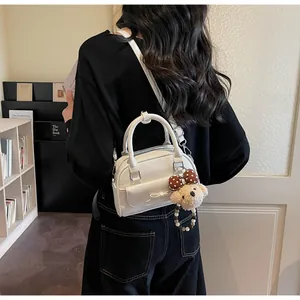 Vue détaillée du sac à main blanc chic avec nœud décoratif et charme d'ours