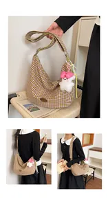 Detail of checkered canvas hobo bag featuring wide strap and plush bunny charm