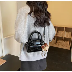 Détail du sac bandoulière noir en similicuir avec un nœud chic et un porte-clé ours