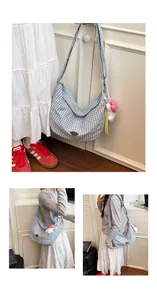 Detail of blue and white checkered canvas hobo bag with gold logo and plush sheep charm
