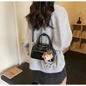 Détail d'un sac bowling noir brillant avec un charmant ours en peluche et perles