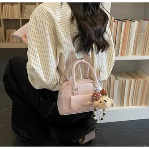 Gros plan sur un sac polochon rose avec nœud et breloque ours en peluche sur le côté
