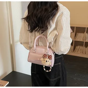 Sac bandoulière rose en similicuir avec charm ours en peluche dans un cadre intérieur